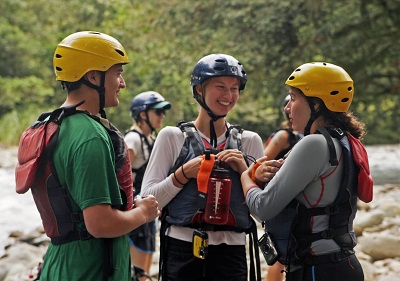 three people wearing helmet and ready to raft in rishikesh