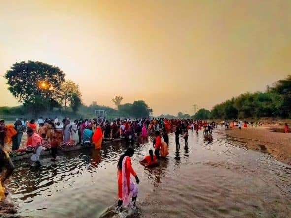 Devotees standing in water to pray to God Sun in Chath puja