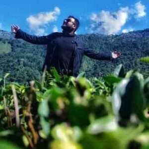 man standing amidst the Tea garden surrounded by green mountains