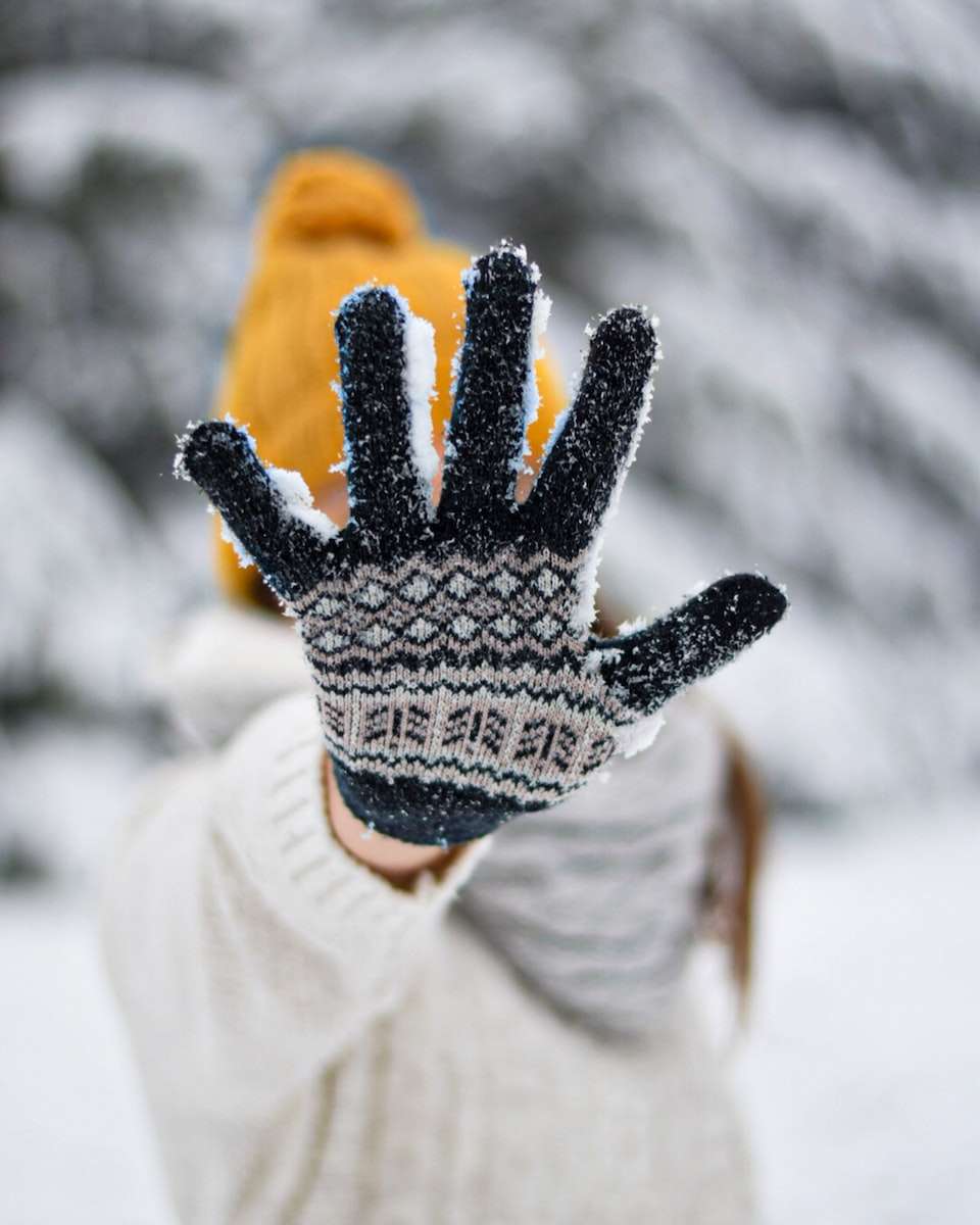 person in white and black knit gloves in winters in manali