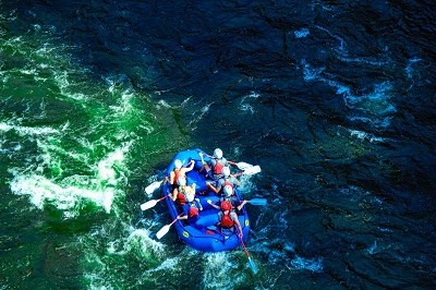 Rafting in Rishikesh in a Rafting Boat wearing life jackets and helmet