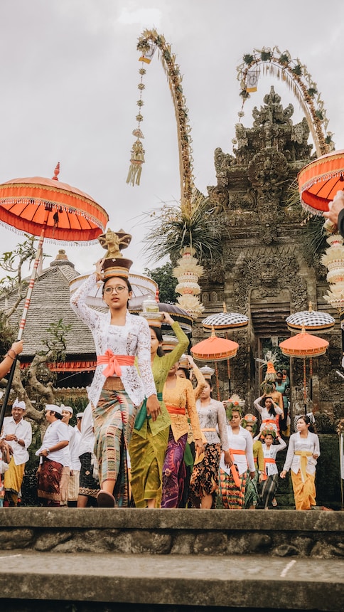 women in traditional dress with flower pots on head during daytime during a cultural festival in Ubud, Bali, Indonesia