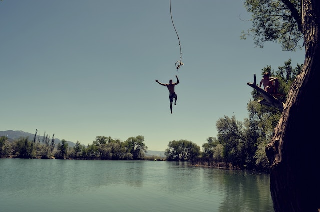 man jumping on body of water with rope and doing adventure in Bali