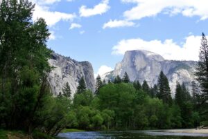 River passing through a valley of snow covered mountains with lush green forest on its bank