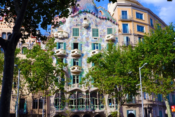 green trees in front of brown concrete building named Casa Batllo in Barcelona during daytime